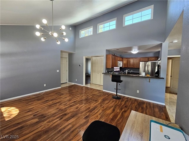 3145 E Flamingo Rd Unit 2005, Las Vegas, NV 89121 - unfurnished living room featuring light wood-type flooring, baseboards, a high ceiling, and an inviting chandelier