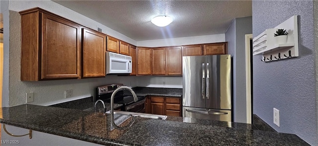 3145 E Flamingo Rd Unit 2005, Las Vegas, NV 89121 - kitchen featuring freestanding refrigerator, white microwave, a textured wall, range with electric stovetop, and a peninsula