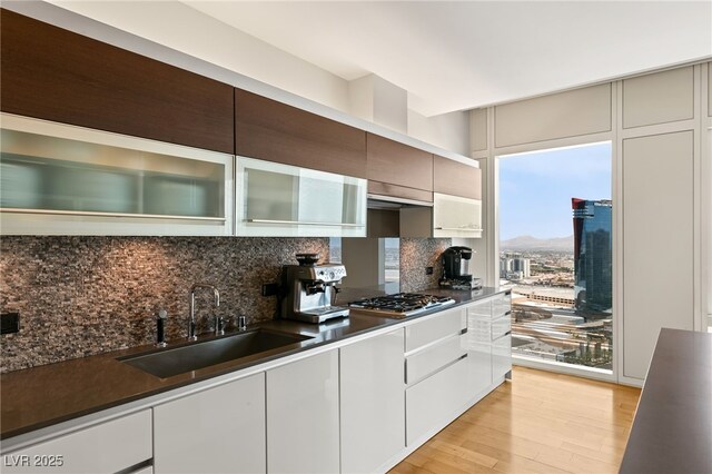 3750 Las Vegas Blvd Unit 3008, Las Vegas, NV 89158 - kitchen with a sink, light wood-type flooring, decorative backsplash, and dark countertops