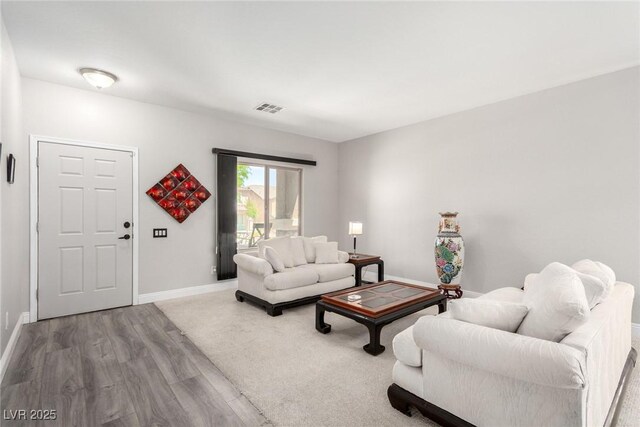 living area with baseboards, wood finished floors, and visible vents