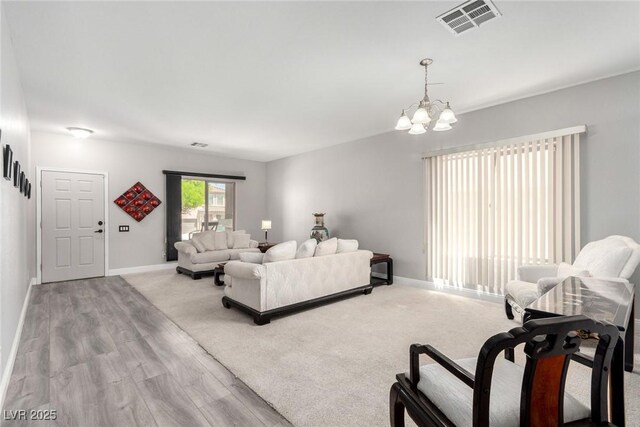 living room with baseboards, a notable chandelier, visible vents, and wood finished floors