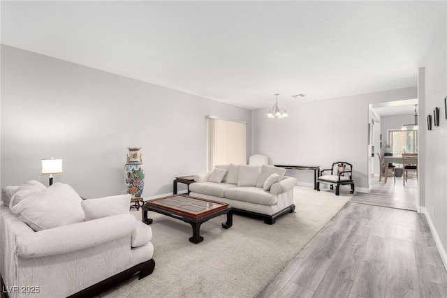 living area with baseboards, wood finished floors, and a notable chandelier