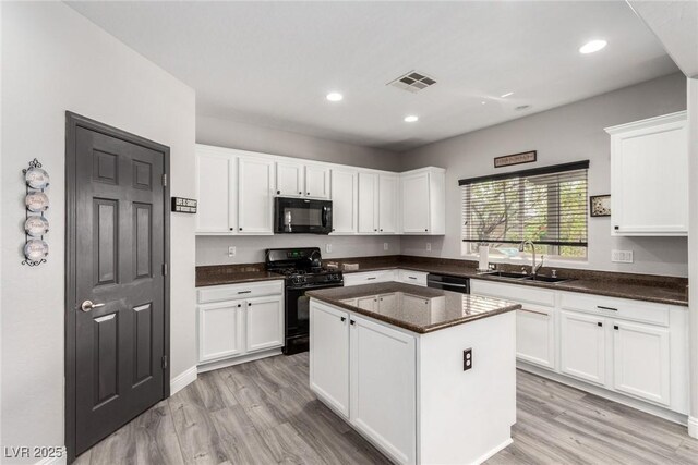 kitchen featuring white cabinets, visible vents, a sink, and black appliances