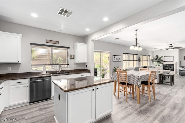 kitchen featuring visible vents, light wood-style floors, open floor plan, a sink, and dishwasher