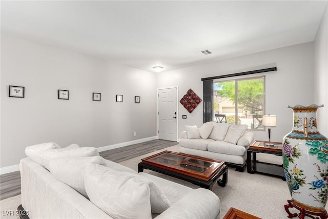 living room with light wood-style floors, baseboards, and visible vents