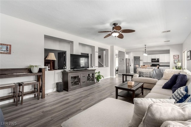 living area featuring baseboards, a ceiling fan, wood finished floors, and visible vents