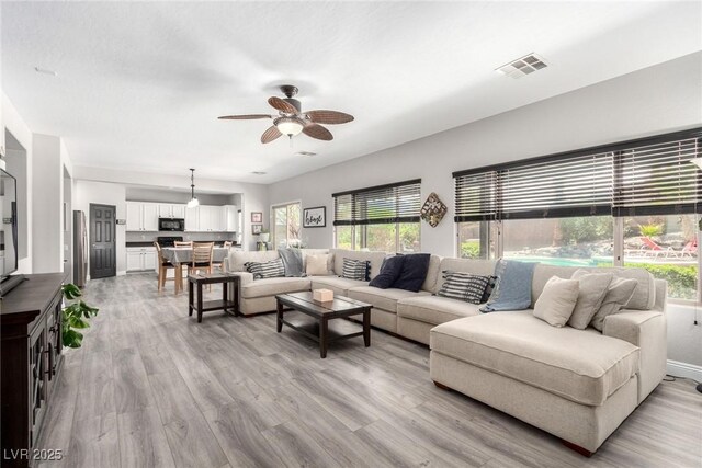 living area with visible vents, light wood-style flooring, and ceiling fan