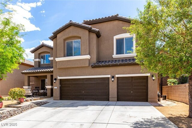 mediterranean / spanish-style home featuring fence, a garage, stucco siding, a tiled roof, and driveway