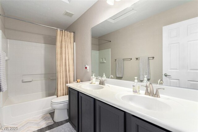 full bath featuring double vanity, a sink, shower / tub combo with curtain, and toilet