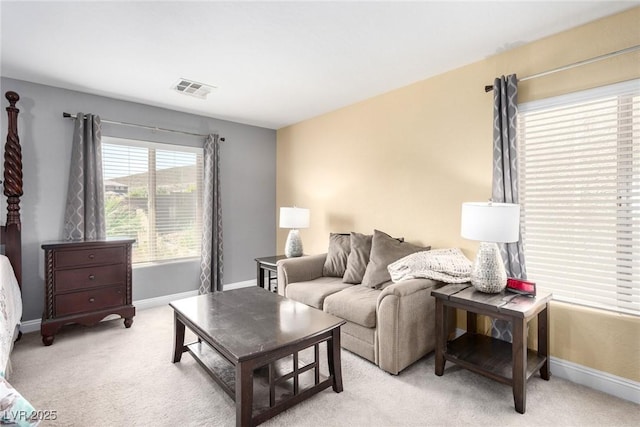 living area featuring baseboards, light colored carpet, and visible vents