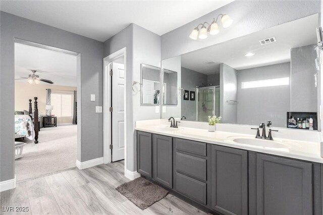 full bathroom featuring ceiling fan, visible vents, wood finished floors, a sink, and connected bathroom
