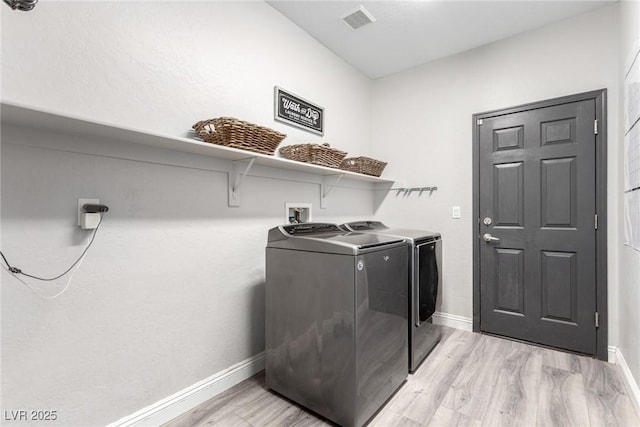 clothes washing area featuring laundry area, light wood finished floors, independent washer and dryer, and visible vents