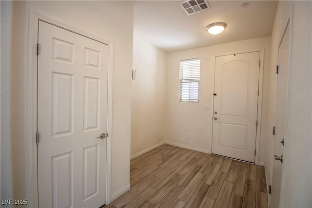foyer entrance featuring light wood-type flooring, baseboards, and visible vents