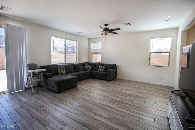 living area featuring light wood finished floors, baseboards, visible vents, and ceiling fan