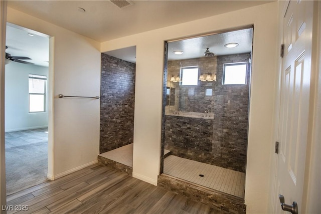 full bathroom featuring visible vents, baseboards, wood finished floors, a ceiling fan, and a walk in shower