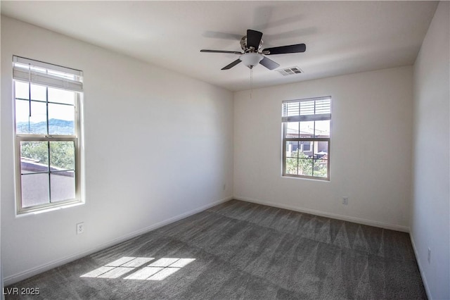 spare room featuring baseboards, visible vents, dark carpet, and a ceiling fan