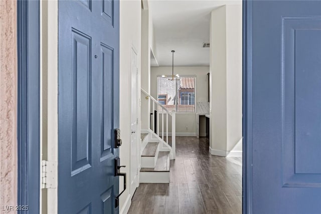 entrance foyer featuring baseboards, stairway, dark wood-type flooring, and a chandelier