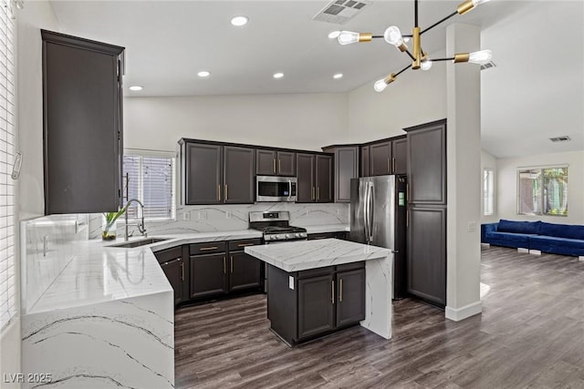 kitchen with a sink, appliances with stainless steel finishes, light stone counters, and visible vents