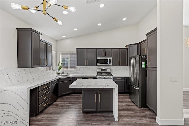 kitchen featuring tasteful backsplash, stainless steel appliances, dark wood-type flooring, a kitchen island, and a sink
