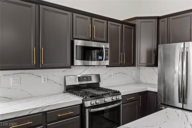 kitchen featuring stainless steel appliances, light stone counters, and decorative backsplash