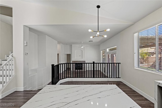 interior space with stairway, vaulted ceiling, an inviting chandelier, baseboards, and dark wood-style floors
