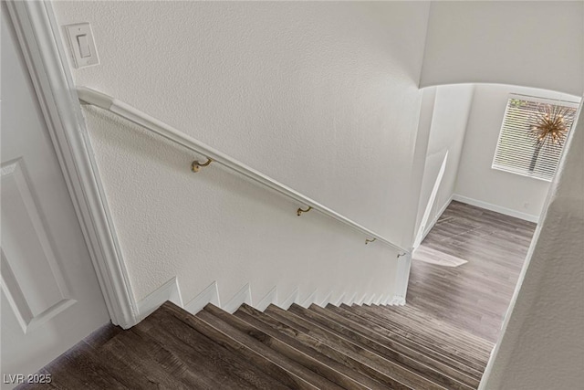 stairs featuring a textured wall and wood finished floors