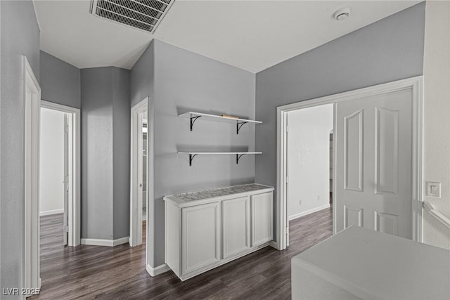 interior space with dark wood-style floors, baseboards, and visible vents