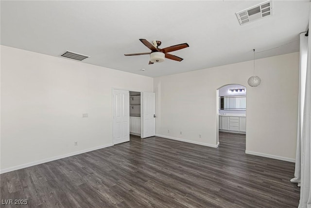 empty room featuring dark wood-style flooring, visible vents, and a ceiling fan