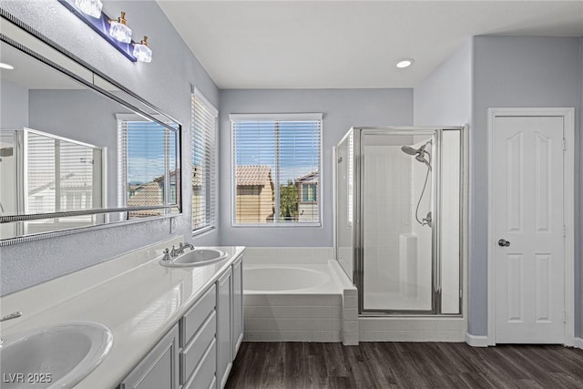 bathroom with a stall shower, wood finished floors, and a sink