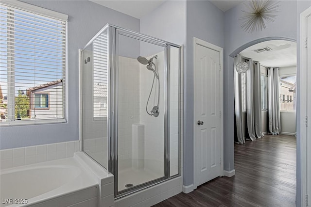 full bath featuring wood finished floors, plenty of natural light, a bath, and a shower stall