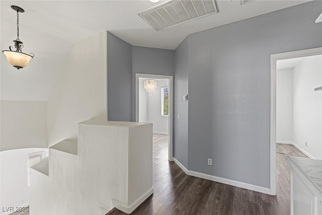 hallway with an upstairs landing, dark wood-style floors, baseboards, and visible vents