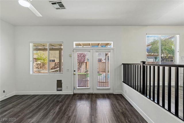 interior space featuring baseboards, visible vents, a ceiling fan, and dark wood-style flooring