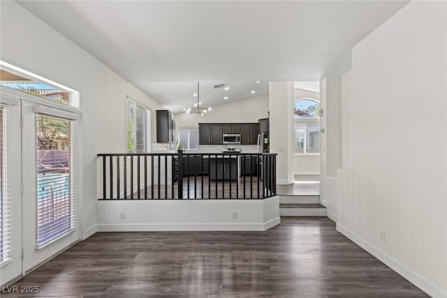 living room featuring a chandelier, dark wood-type flooring, baseboards, and vaulted ceiling