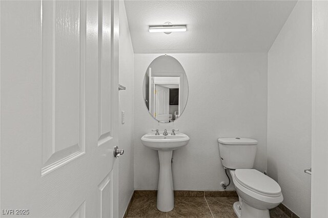 half bathroom featuring toilet, tile patterned floors, and baseboards