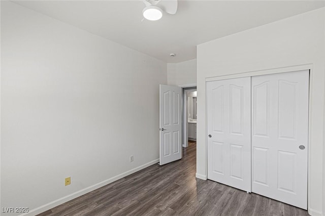unfurnished bedroom featuring dark wood finished floors, baseboards, and a closet