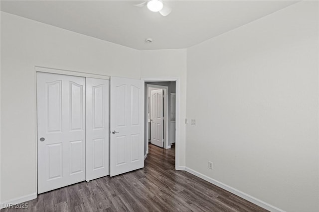 unfurnished bedroom featuring dark wood-style floors, a closet, and baseboards