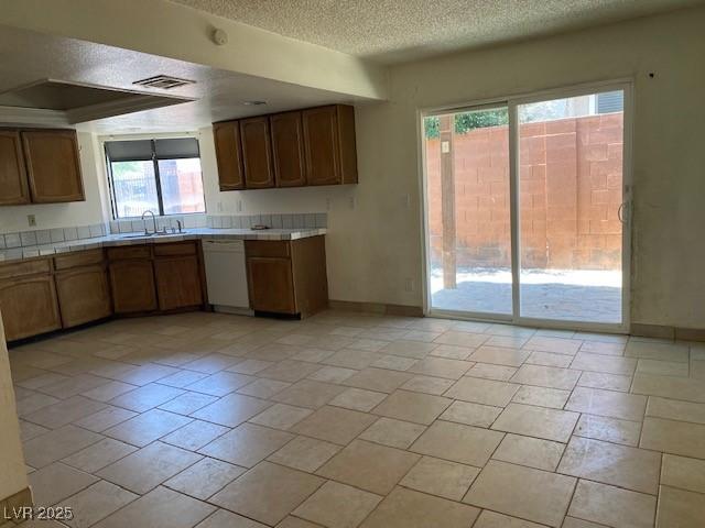 7732 Blackbird Ave, Las Vegas, NV 89145 - kitchen featuring dishwasher, a textured ceiling, and tile counters