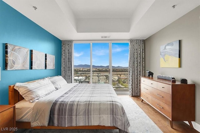 150 Las Vegas Blvd Unit 918, Las Vegas, NV 89101 - bedroom with expansive windows, a tray ceiling, a mountain view, and light wood-type flooring
