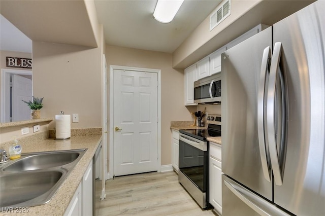 8000 Badura Ave Unit 2063, Las Vegas, NV 89113 - kitchen with appliances with stainless steel finishes, a sink, white cabinets, and light wood-style floors