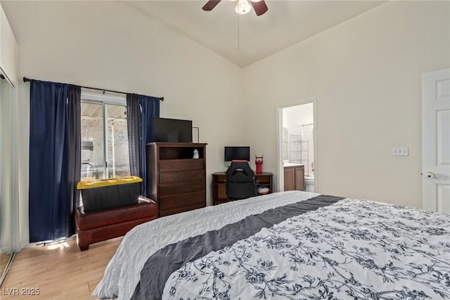 bedroom with wood finished floors, high vaulted ceiling, ceiling fan, and ensuite bath