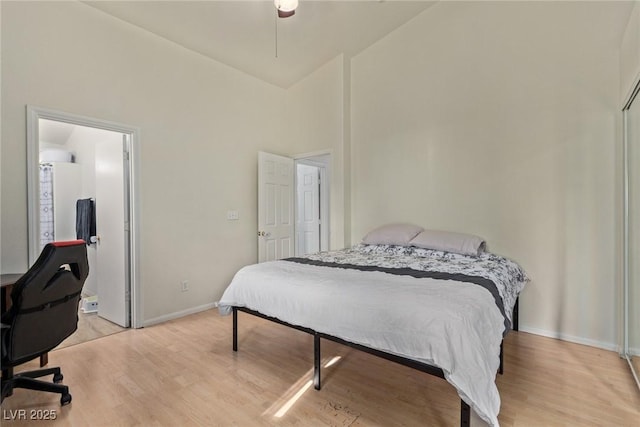 bedroom featuring high vaulted ceiling, light wood-style floors, and baseboards