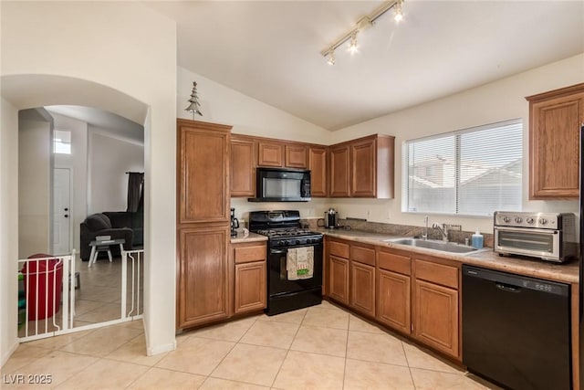 kitchen with arched walkways, a sink, black appliances, and light tile patterned flooring