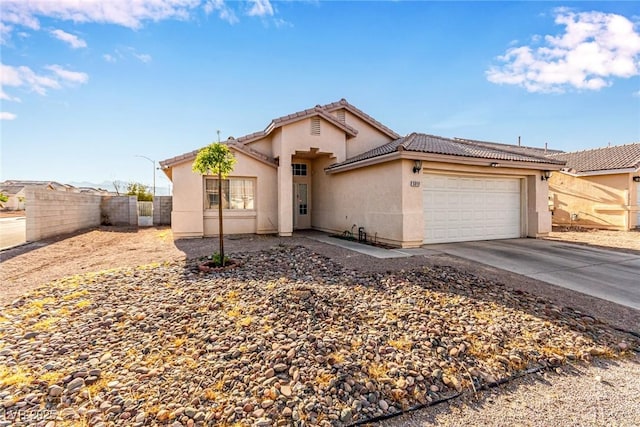 view of front facade with a tiled roof, stucco siding, fence, an attached garage, and driveway