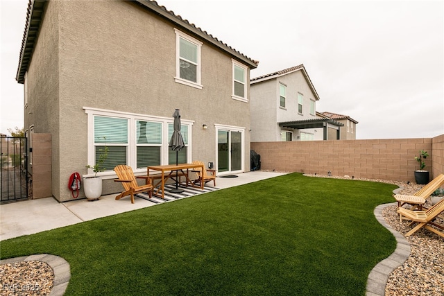 back of house with stucco siding, fence, and a tile roof