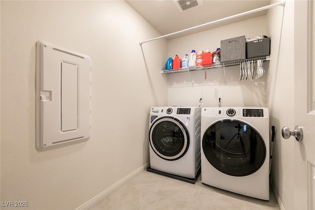 laundry area featuring laundry area, separate washer and dryer, light tile patterned flooring, and baseboards