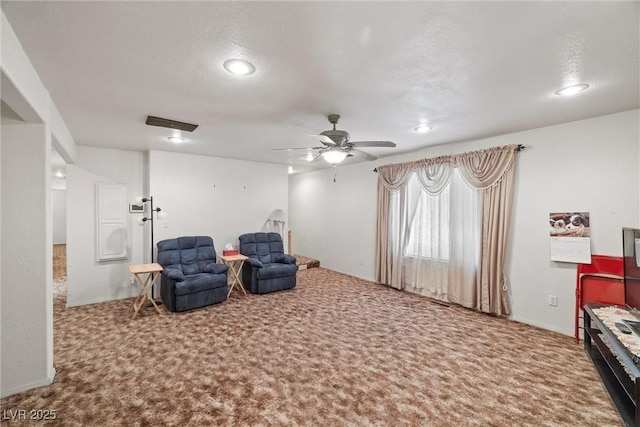living area featuring a textured ceiling, carpet, and a ceiling fan