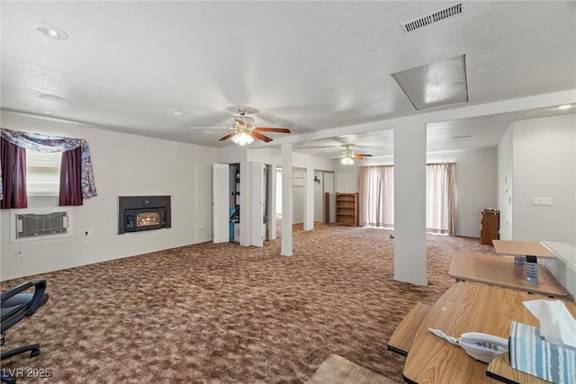 carpeted living area with a wall mounted AC, visible vents, and a ceiling fan