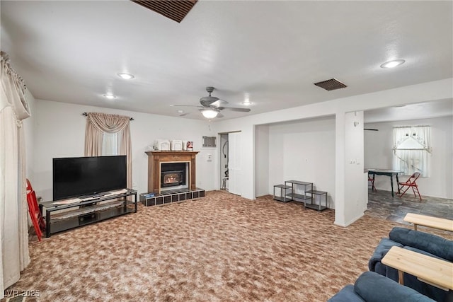 living area with a fireplace, a ceiling fan, visible vents, and carpet