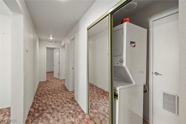 washroom featuring stacked washer and clothes dryer, carpet floors, laundry area, and visible vents