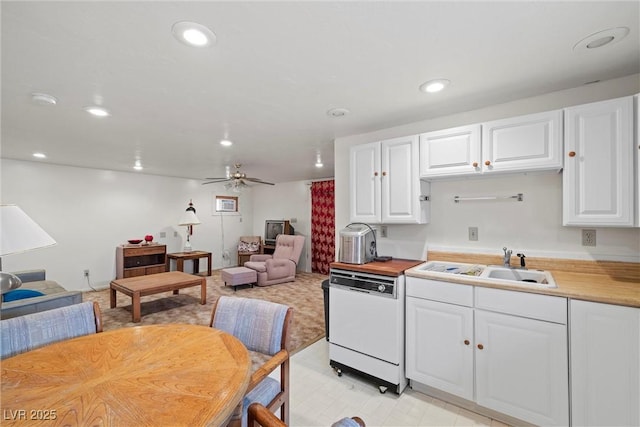 kitchen with white cabinets, recessed lighting, a sink, open floor plan, and white dishwasher
